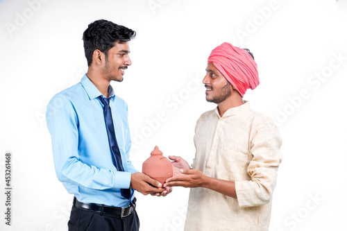 Saving concept : Young indian banker and farmer holding clay piggy bank in hand photo