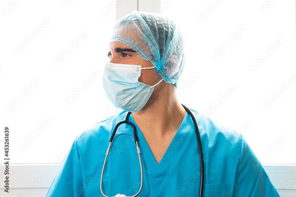 Male doctor standing in hospital with hat and face mask Male doctor standing in hospital with hat and face mask