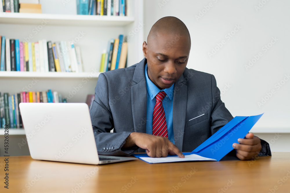 African american mature businessman working with paperwork at desk at office African american mature businessman working with paperwork at desk at office