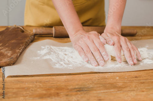 A woman baker or pastry chef kneads the dough. Close-up.