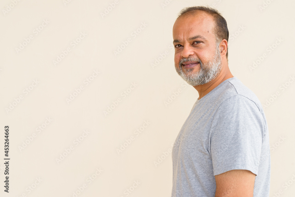 Portrait of happy bearded Indian man smiling against plain wall Portrait of happy bearded Indian man smiling against plain wall