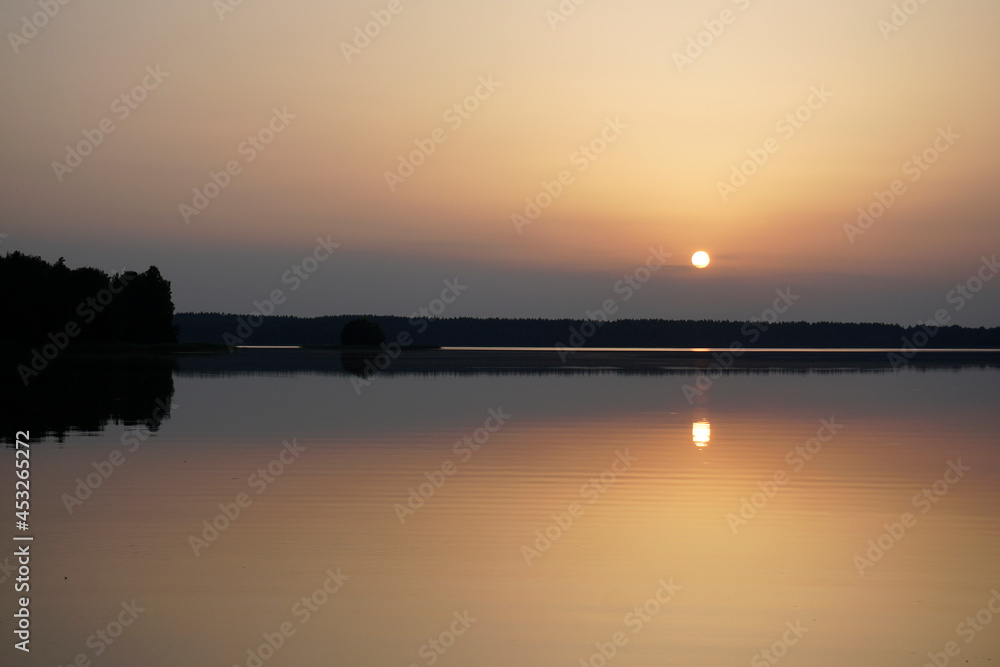 Quiet evening after a sultry day. Beautiful sunset over the lake. Reflection and horizon. Evening dim soft sun Quiet evening after a sultry day. Beautiful sunset over the lake. Reflection and horizon. Evening dim soft sun