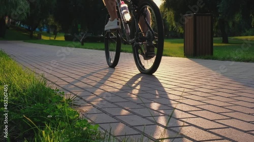 A young man rides a bicycle in a city park at sunset. Summer active holidays