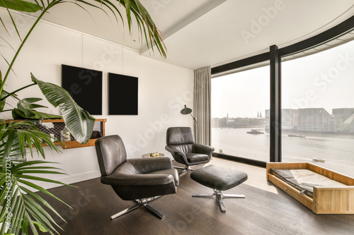 Modern apartment interior with leather chairs near window