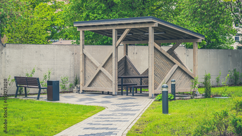 Wooden gazebo for relaxing in the yard. Green lawn.