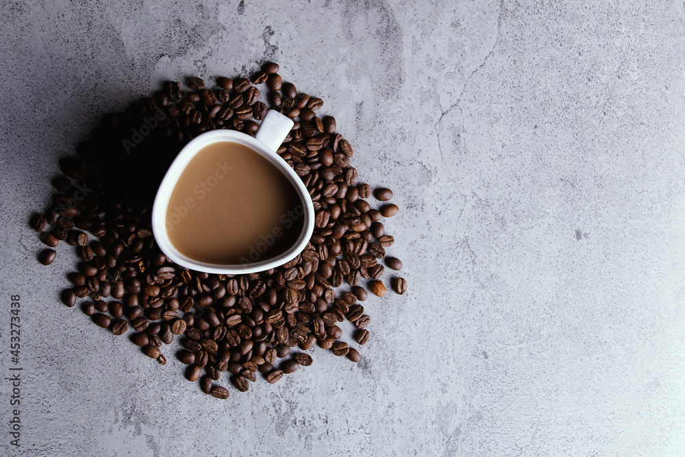 Top view. A cup of cappuccino coffee surrounded by coffee beans in the middle of a texture table. Top view. A cup of cappuccino coffee surrounded by coffee beans in the middle of a texture table.