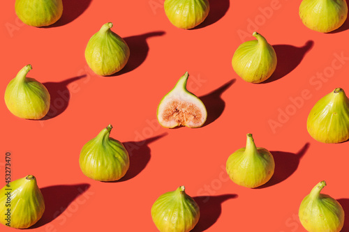 Pattern made of fresh organic mediterranean figs on bright terracotta background. Modern design arrangement.