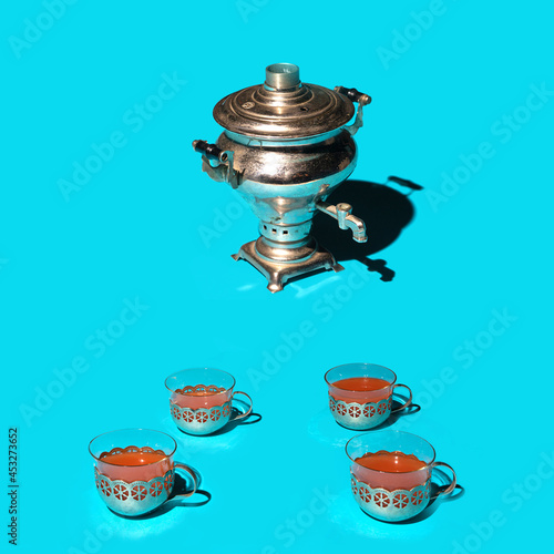 Tea enjoyer concept. Antique silver samovar self brewer with four tea cups against blue background. photo