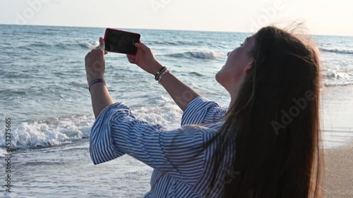 Young woman taking pictures of the sea as a keepsake 