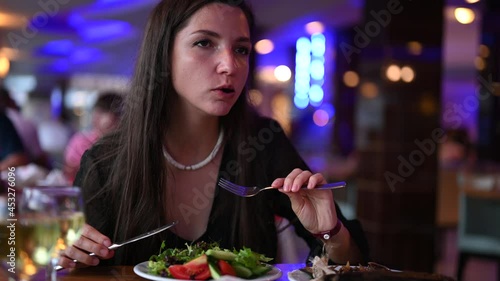 Vegetarian woman enjoying vegetable salad, evening in restaurant 