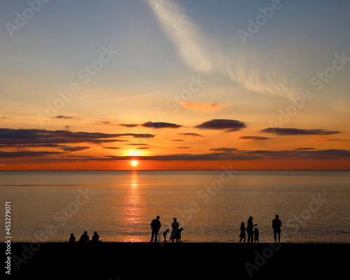 Silhouetted people at sunset on the Welsh coast - family playing in the golden light