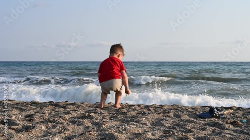 Lonely child, playing alone, by the sea 