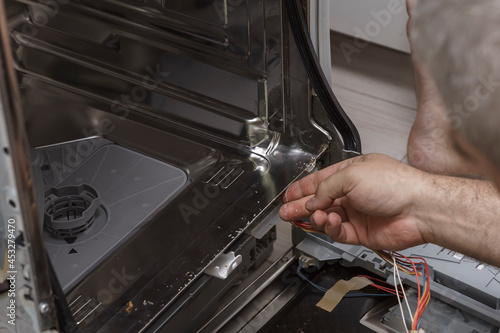 People in technician jobs. Appliance repair technician works on broken dishwasher in a kittchen.