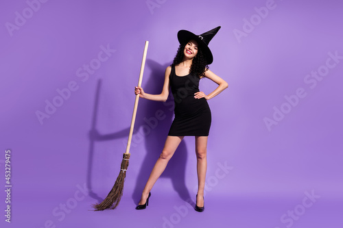 Full size photo of happy smiling lovely charming woman witch hold broomstick isolated on violet color background