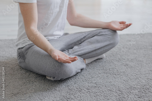 Fototapeta Naklejka Na Ścianę i Meble -  a European man meditates in his spacious and cozy apartment, sports or yoga, meditation and breathing practices at home, a Caucasian young adult man meditates in his own clothes, mental and physical