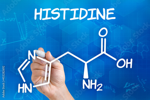 Hand with pen drawing the chemical formula of histidine photo