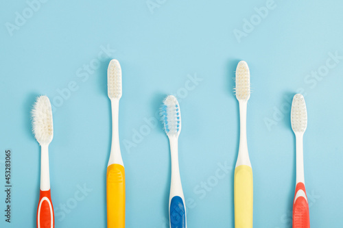 The old toothbrush used expired (damaged) variety of colors on the blue background. concept Used for manufacturing health industry Professional dentist or often should change your toothbrush.