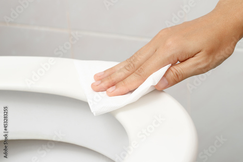 woman using tissue paper clean the toilet in the bathroom at home.