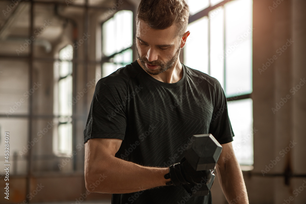 Muscular man exercising with dumbbells in gym Muscular man exercising with dumbbells in gym