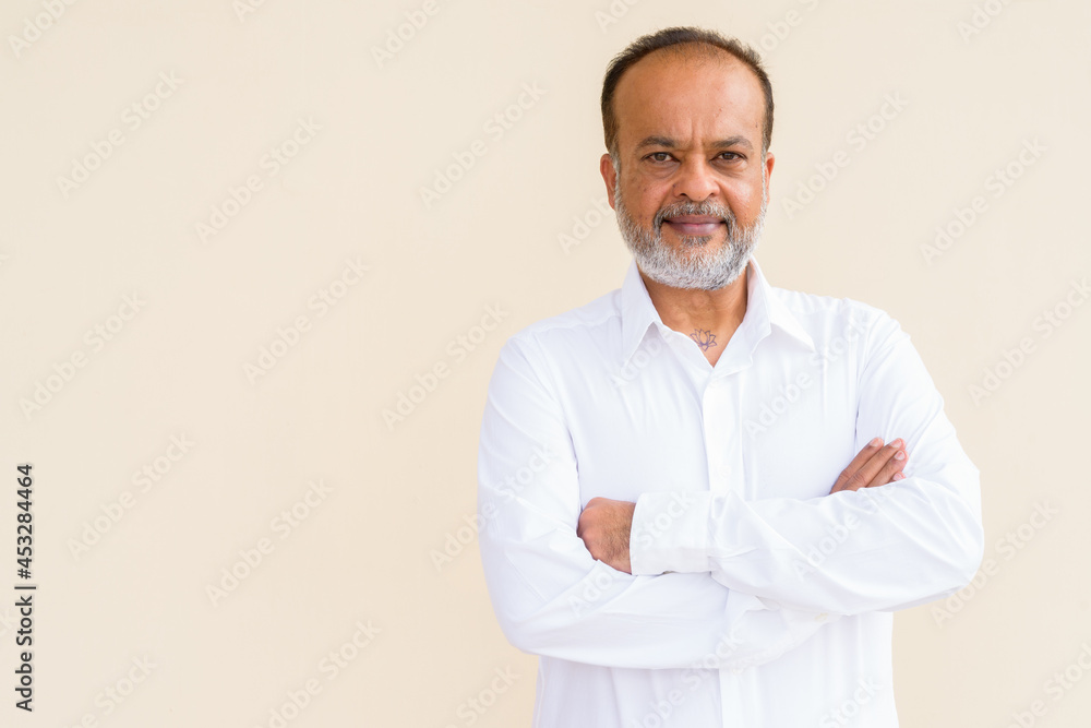 Portrait of handsome bearded Indian man against plain wall Portrait of handsome bearded Indian man against plain wall