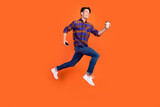 Photo of hurrying teenager man dressed checkered clothes jumping running holding coffee phone isolated orange color background