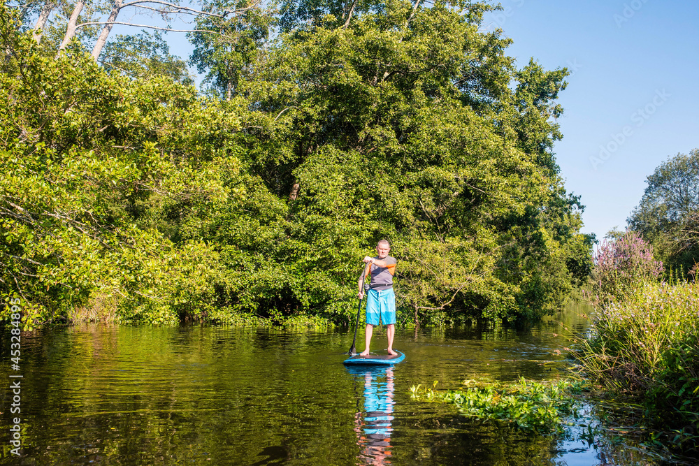 middle aged man paddle boarding on a river middle aged man paddle boarding on a river