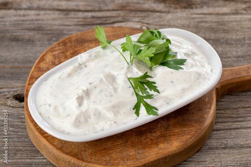 Haydari on a wooden background. Haydari is a type of yogurt made from certain herbs and spices, combined with garlic. Turkish cuisine. Close up, selective focus