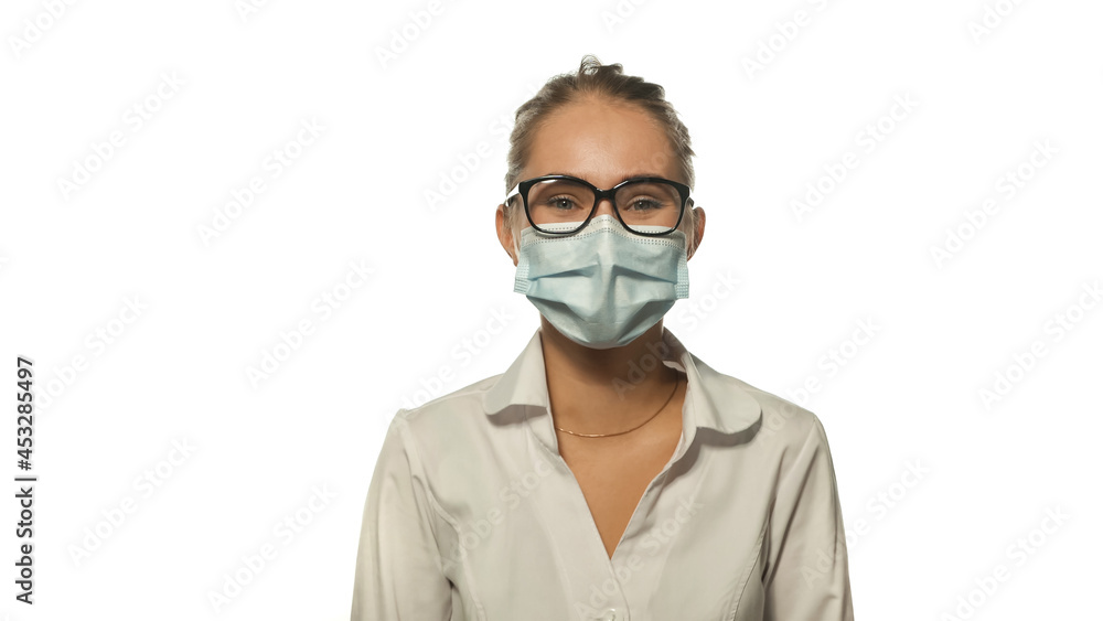 Positive looking young blond nurse in eye glasses looking at the camera wearing white medical uniform isolated on white background. Positive looking young blond nurse in eye glasses looking at the camera wearing white medical uniform isolated on white background.