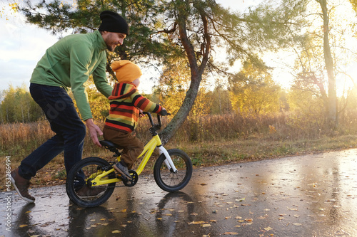 Tela Father teaches his little child to ride bicycle in autumn park