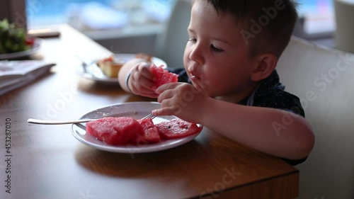 A child enjoys a watermelon in the evening in a restaurant