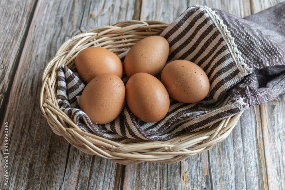 Brown chicken eggs in the wooden basket with cute fabric, close-up view. Brown chicken eggs in the wooden basket with cute fabric, close-up view.