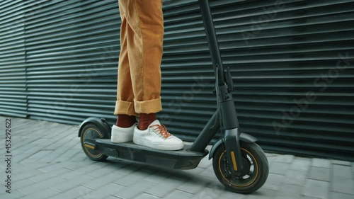 Low section shot of legs of unrecognizable man riding electric scooter on urban street