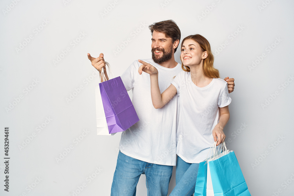 young couple in white t-shirts with bags in hands shopping fun