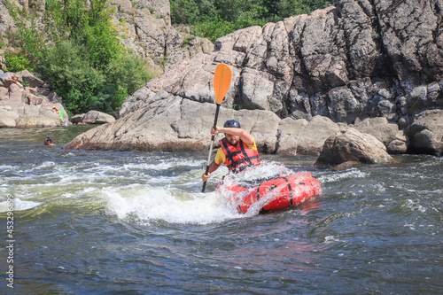 A man rowing inflatable packraft on whitewater of mountain river. Concept: summer extreme water sport,  active rest, extreme rafting. © Oleksandra