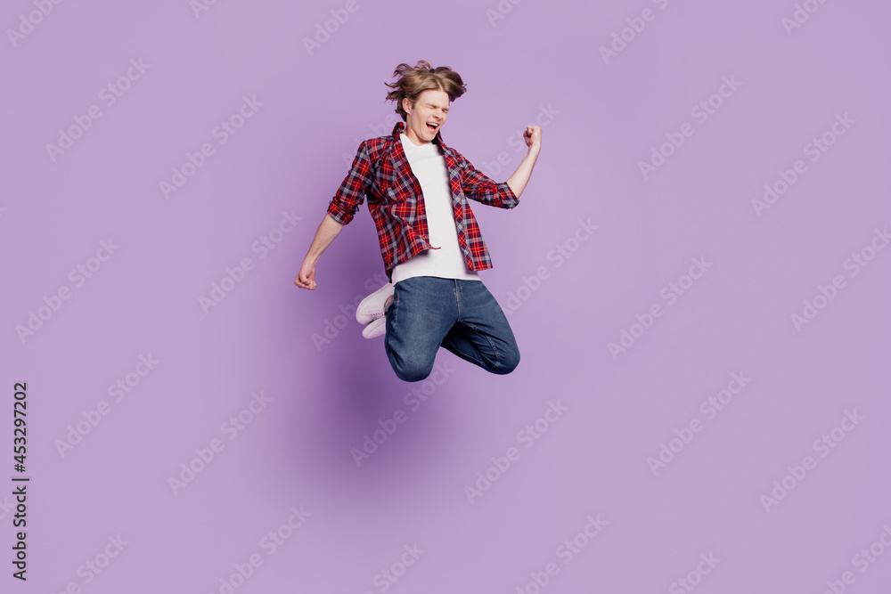 Portrait of carefree joyful casual trendy stylish guy jump achieve triumph on violet background Portrait of carefree joyful casual trendy stylish guy jump achieve triumph on violet background