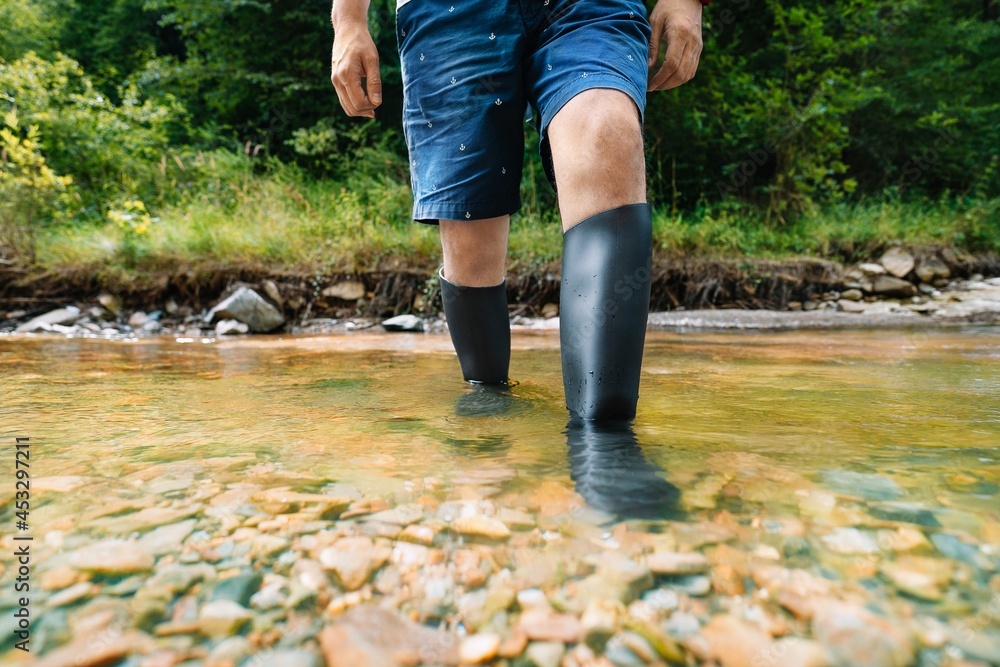 Man with rubber boots walking in the river Man with rubber boots walking in the river