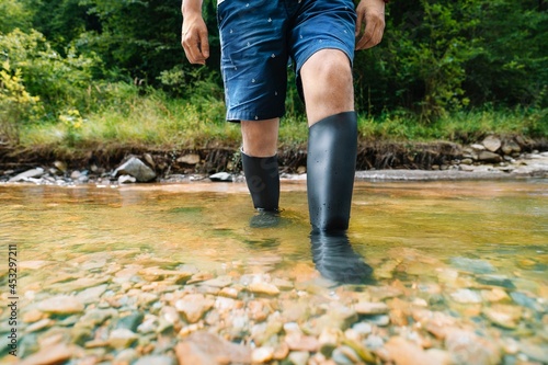 Man with rubber boots walking in the river