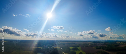 The light of the sun shining through the clouds in the sky. Amazing of fluffy clouds moving softly on the sky and the sun shining through the clouds with beautiful rays and lens flare. Space for text.