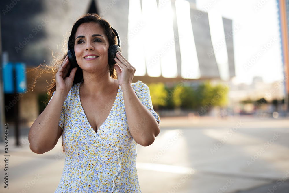 Young smiling woman with headphones outdoors. Beautiful woman listening the music.