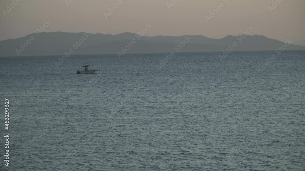 View of a fish boat crossing the sea in sunset View of a fish boat crossing the sea in sunset