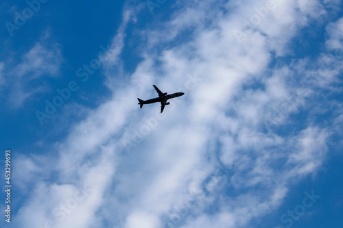Silhouette of airplane flying in blue sky with white clouds in Vietnam