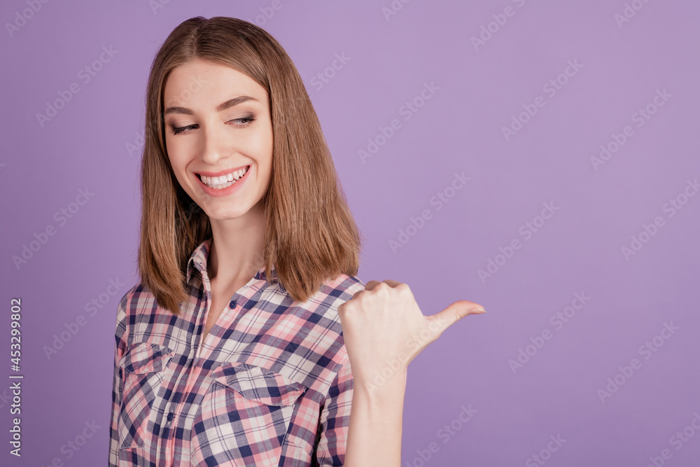 Portrait of positive cheerful girl look indicate thumb copyspace present adverts promo isolated over violet color background Portrait of positive cheerful girl look indicate thumb copyspace present adverts promo isolated over violet color background