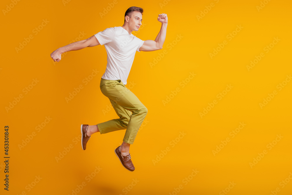 Portrait of funky positive guy jump fly run fast empty space on yellow background
