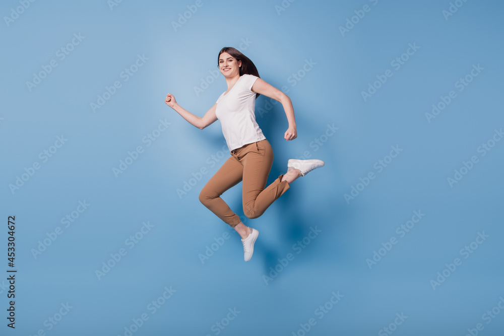 Portrait of sporty energetic active runner lady jump hurry run on blue background