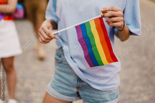 White woman holding rainbow flag during pride parade at street