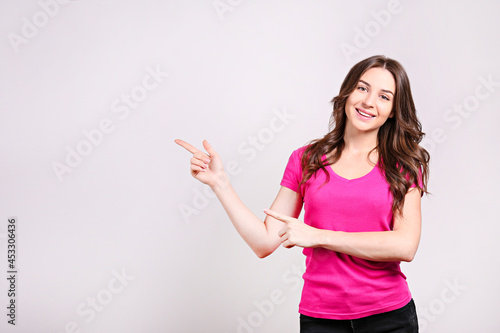 Young beautiful brunette woman with long wavy hair wearing pink shirt, posing over white isolated background. Portrait of female model showing gestures and emotions. Close up, copy space.