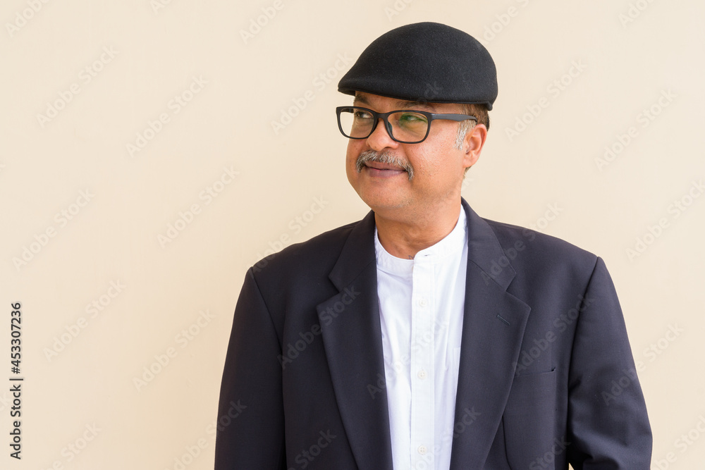 Portrait of handsome Indian businessman with mustache wearing hat against plain wall Portrait of handsome Indian businessman with mustache wearing hat against plain wall