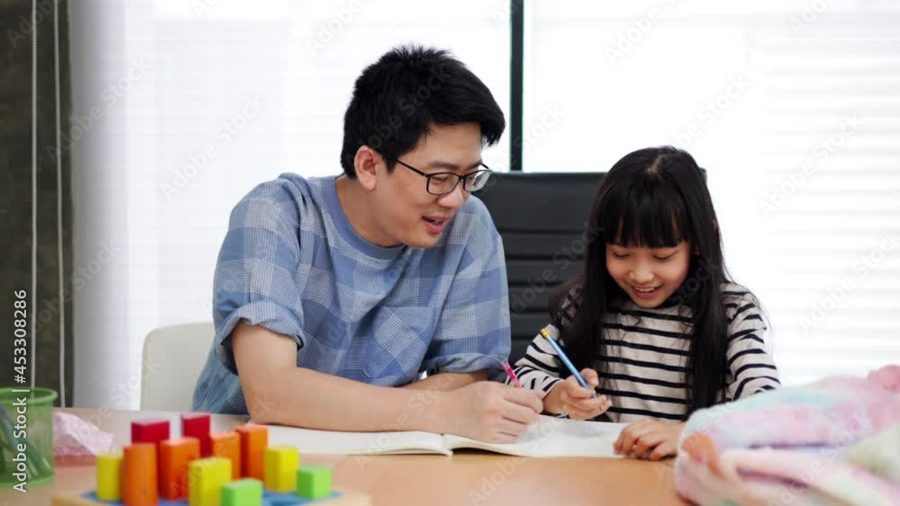 Asian dad and daughter drawing with pencils at table coloring picture together talking at home, young father teaching helping child girl learning creative activity, parent and kid playing. Asian dad and daughter drawing with pencils at table coloring picture together talking at home, young father teaching helping child girl learning creative activity, parent and kid playing.
