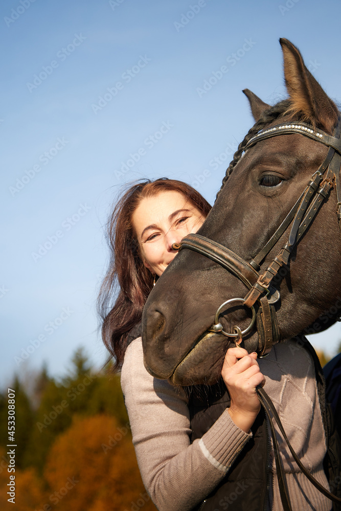 Obraz premium Woman riding a horse in filed in autumn day and blue sky background