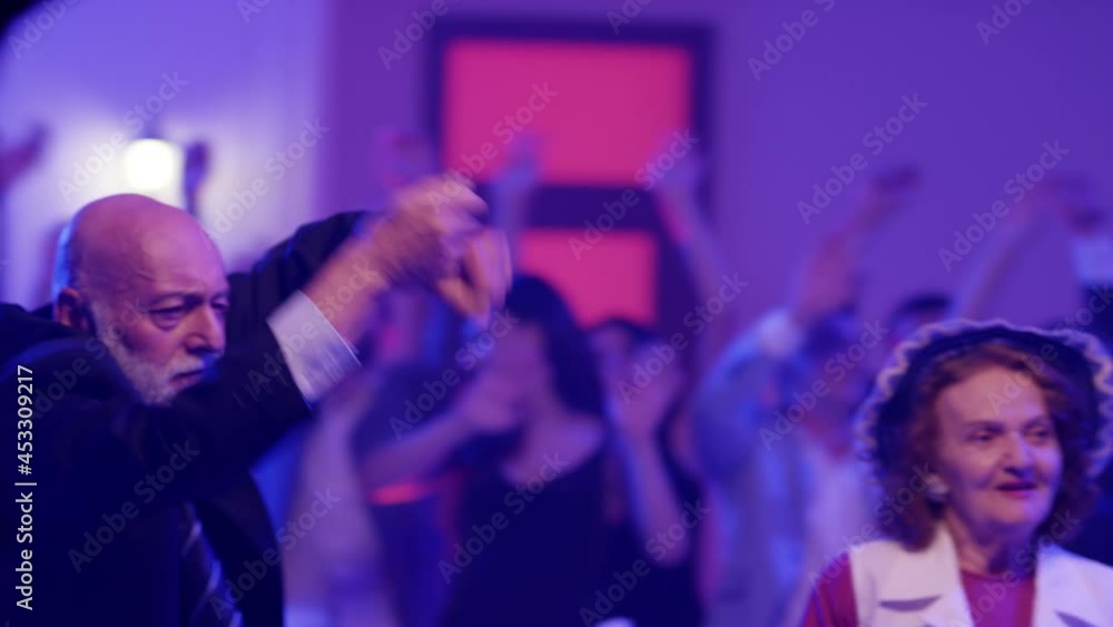 Stylish elderly couple having fun dancing at a colorful party . Sweet senior couple smiling and partying during party . Active retirement . Shot on RED HELIUM Cinema Camera Stylish elderly couple having fun dancing at a colorful party . Sweet senior couple smiling and partying during party . Active retirement . Shot on RED HELIUM Cinema Camera